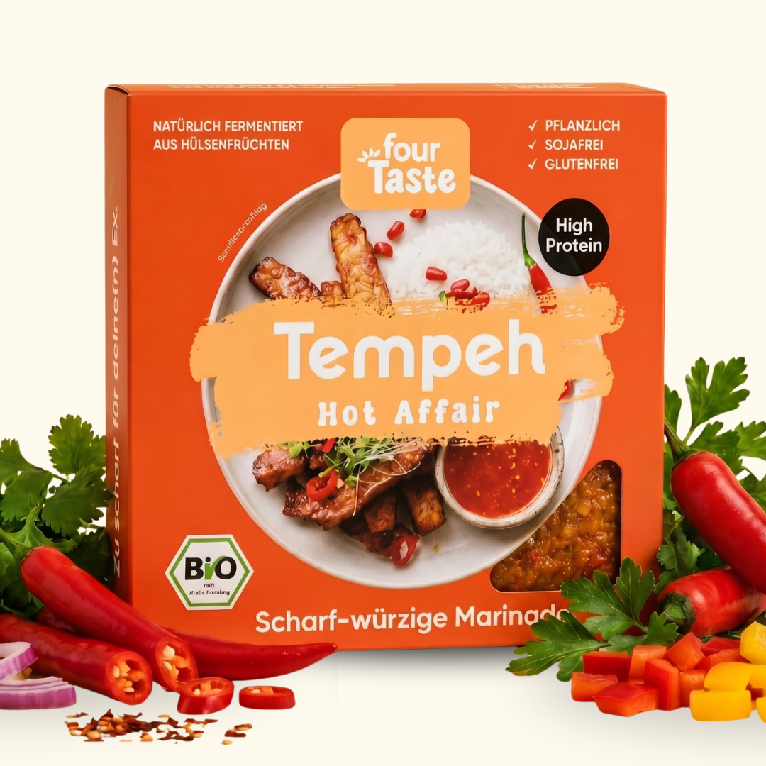 Verpackung des fourTaste Tempeh Hot Affair mit scharf-würziger Marinade. Der fermentierte Bio-Tempeh aus Hülsenfrüchten ist pflanzlich, sojafrei und glutenfrei. Rund um die Verpackung liegen Chili, Kräuter und Gewürze.