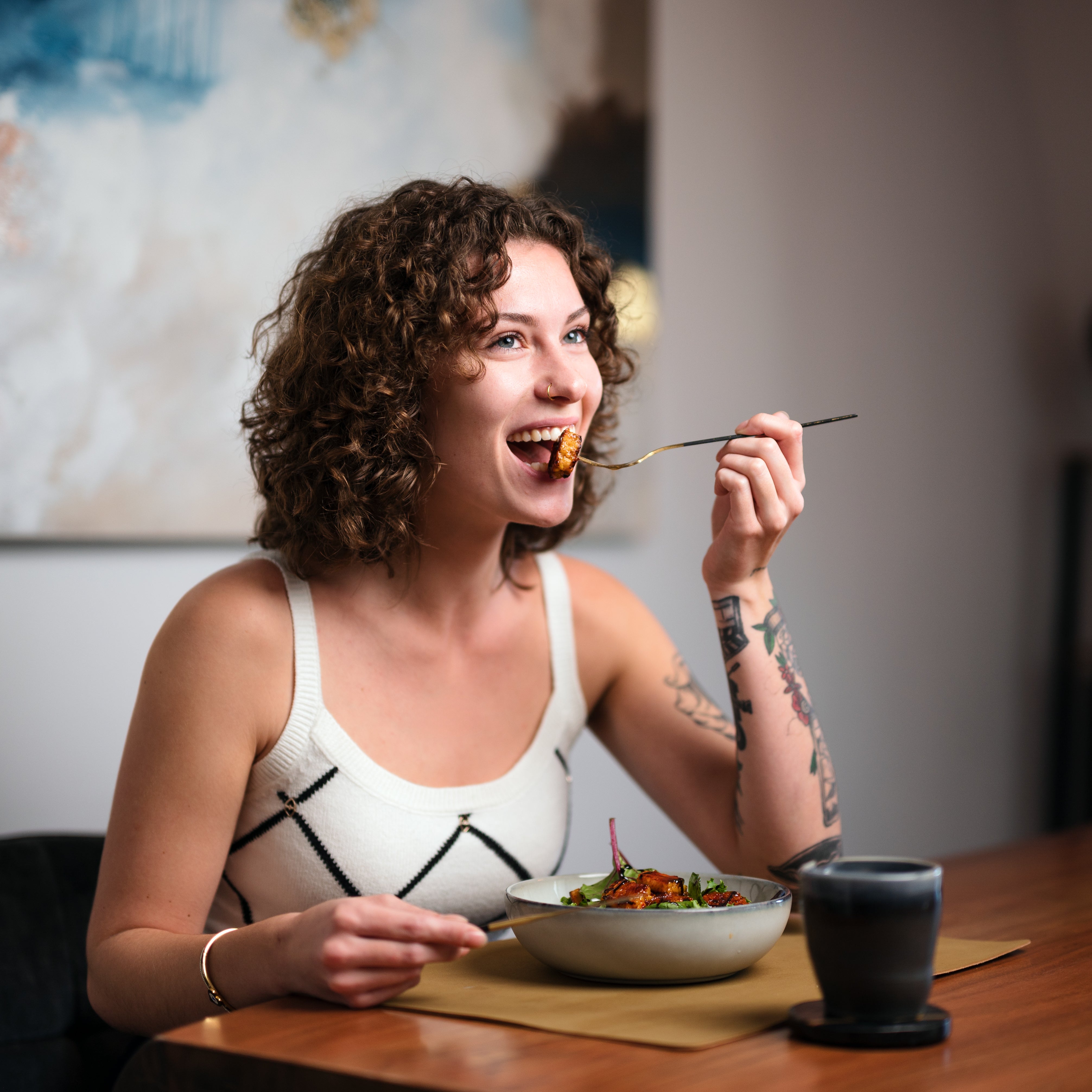 Frau isst Tempeh-Gericht mit Tamari, genießt vollmundigen Umami-Geschmack.