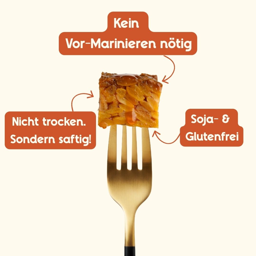 Ein goldbraun angebratenes, scharf mariniertes Stück Tempeh auf einer goldenen Gabel; Infografik-Hinweise betonen: kein marinieren nötig, soja- und glutenfrei sowie 'nicht trocken. sondern saftig.'.