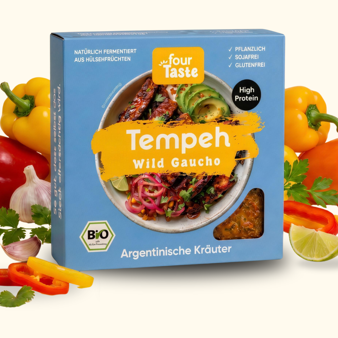 Verpackung des fourTaste Tempeh Wild Gaucho mit argentinischer Kräutermarinade. Der fermentierte Bio-Tempeh aus Hülsenfrüchten ist pflanzlich, sojafrei und glutenfrei. Rund um die Verpackung liegen Paprika, Knoblauch, Kräuter und Limette.