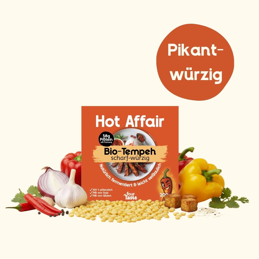 Eine Packung "Hot Affair" Bio-Tempeh in orangefarbener Verpackung, dekoriert mit Chilischoten, Knoblauch und gelber Paprika; ein runder Badge markiert den Geschmack als „pikant & würzig“.